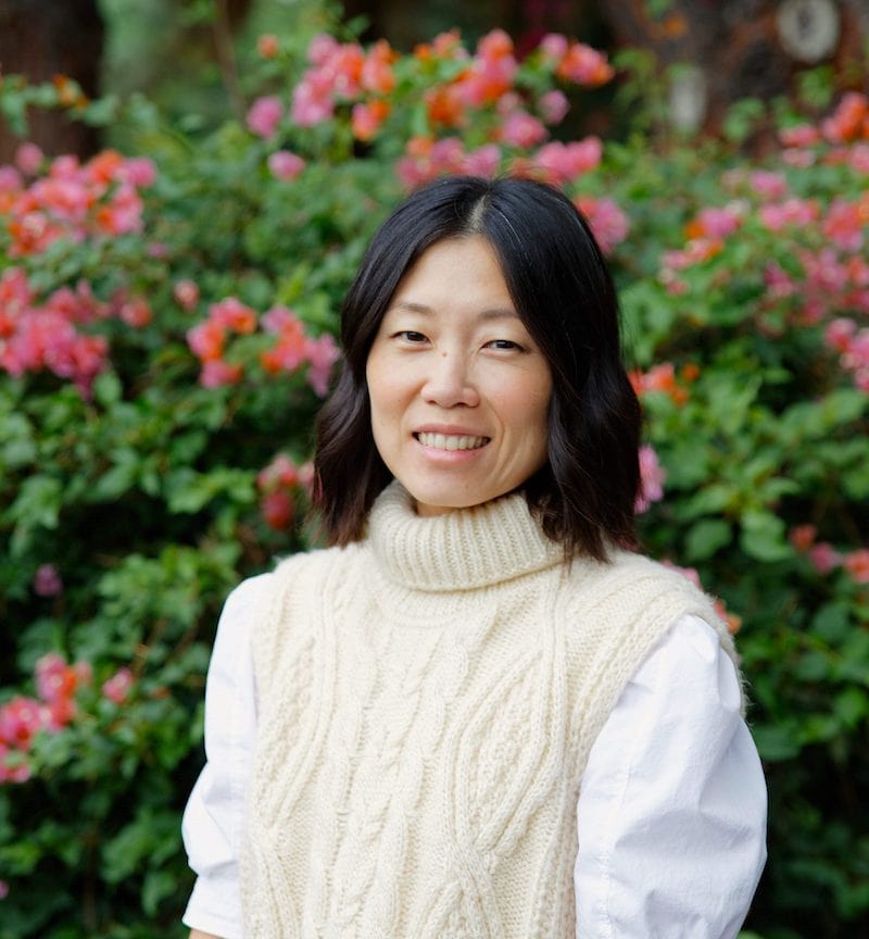 Kathy Kim smiling in front of pink flowers