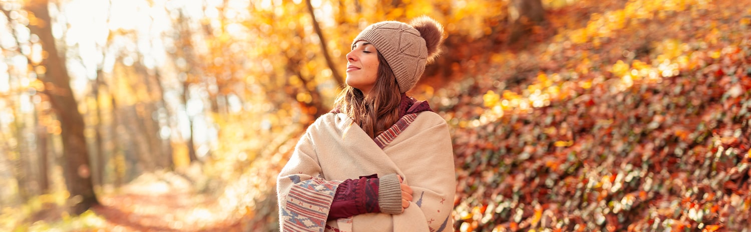 woman bundled up outdoors breathing in fall air