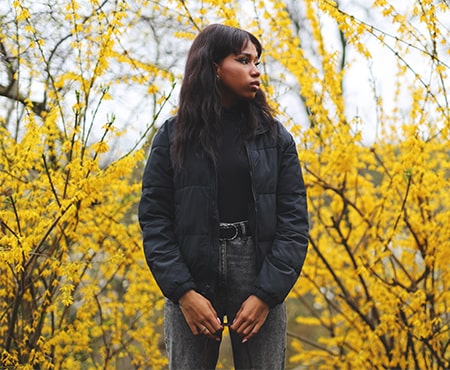 woman standing in front of yellow trees looking off to the side