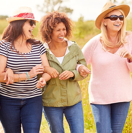 three women linking arms smiling together